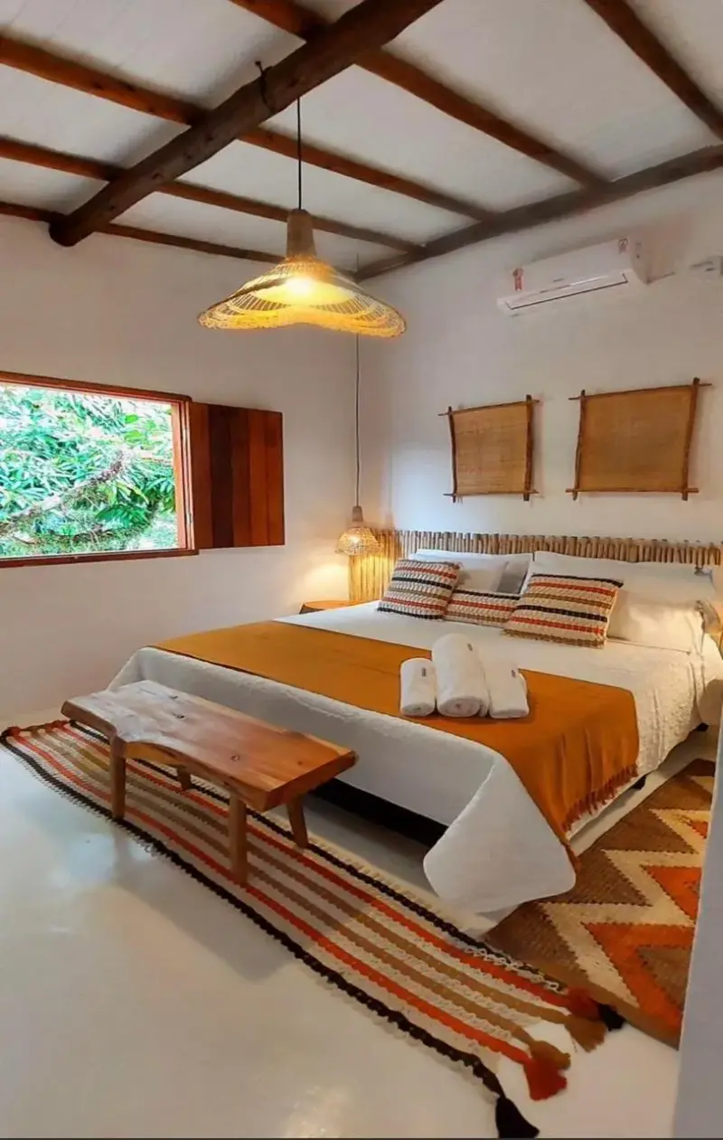 Suíte Almescar com cama de casal, colcha em tons de terracota, teto de madeira, ar-condicionado e janela para o verde
